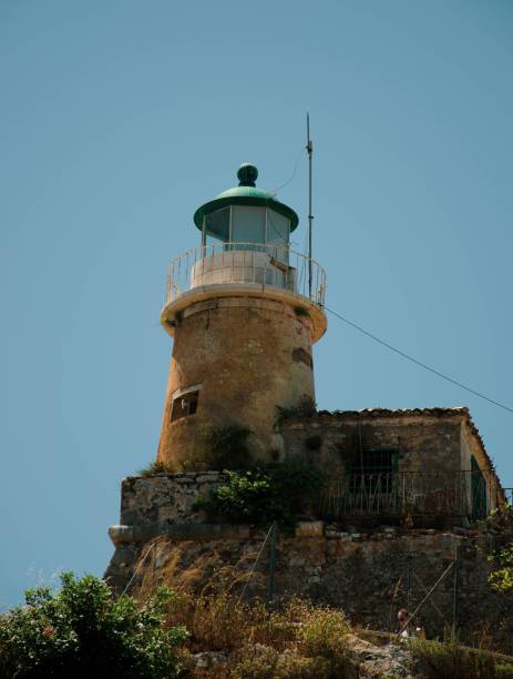 majestuoso y envejecido faro con una cúpula verde sobre una roca contra un cielo azul - perch rock lighthouse fotografías e imágenes de stock