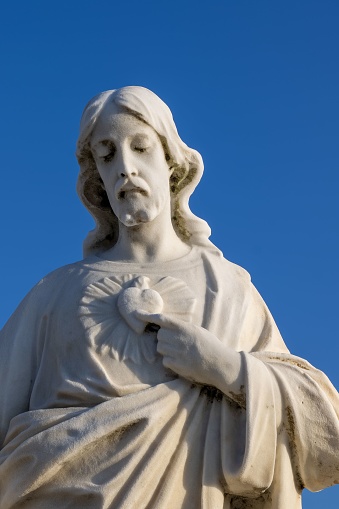 A white statue of Jesus against a backdrop of a bright blue sky