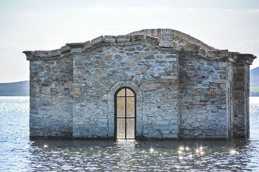 Ancient stone edifice situated in the middle of a body of water, with a wide, open entrance