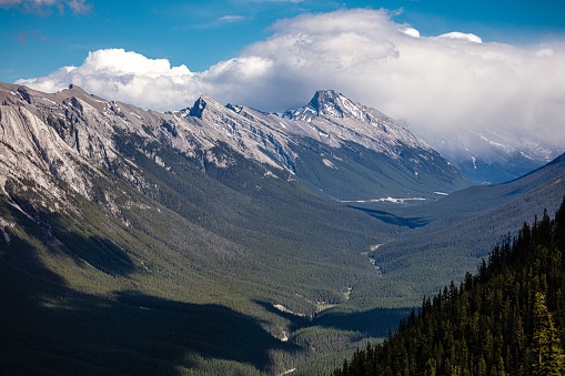 A scenic view of a green valley surrounded by rocky mountains. Banff National Park, Alberta, Canada.