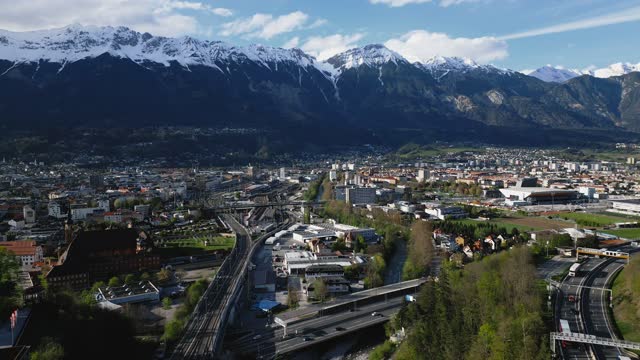 Drone footage over a cityscape with traffic cars and mountains landscape in Innsbruck, Austria