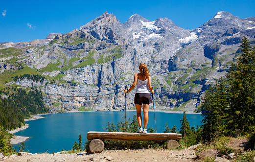 Woman tourist looking at impressive view of Oeschinen lake,  Swiss Alps mountain- Switzerland