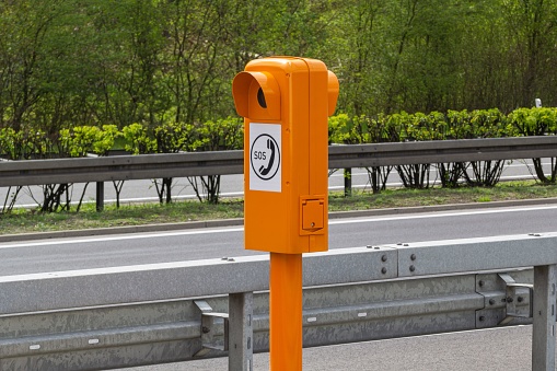An outdoor yellow sos post stands in a city street