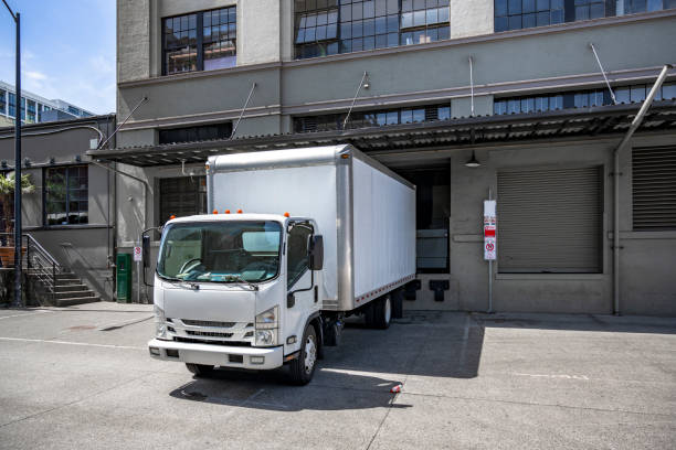 A partially full semi-truck seen from the rear doors containing pallets loaded with plastic covered cargo in the front section. Copy space