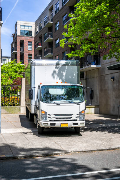 istock Maneuverable white compact cab over small light duty rig semi truck with long box trailer standing on the urban city street unloading delivered cargo 1492810578