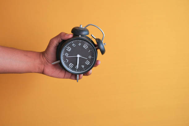 istock person hand holding alarm clock white background , 1492810888