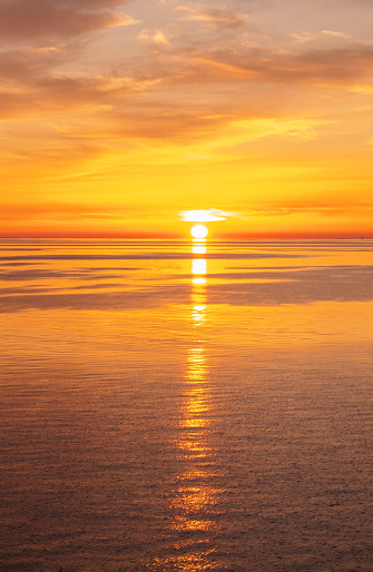 Bright orange sunset in the sea. Clouds and horizon line in the sea.