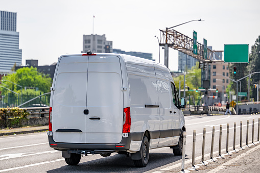 Commercial compact industrial standard white cargo mini van with spacious cargo compartment for different small business use and local delivery request driving on the urban city street road