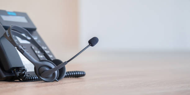 istock Communication support, call center and customer service help desk. VOIP headset on telephone keyboard. 1492813156