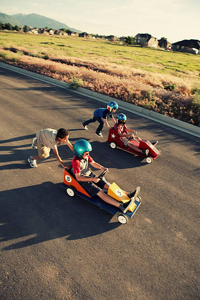 Down The Stretch A group of young neighborhood boys race their go-carts for the street championship. soapbox cart stock pictures, royalty-free photos & images