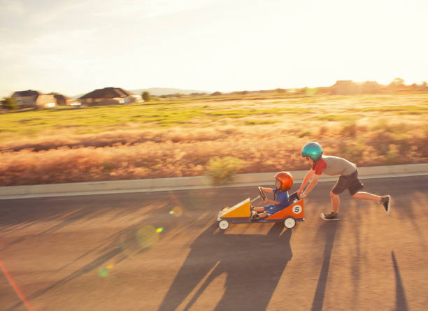 Racing Kids A young racing duo hits the road in their pursuit of conquering speed. soapbox cart stock pictures, royalty-free photos & images