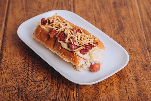 A delicious and juicy hot dog served on a soft and lightly toasted bun on a wooden table.