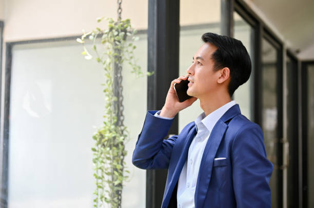 istock A successful Asian businessman is on the phone while standing by the window 1492822289