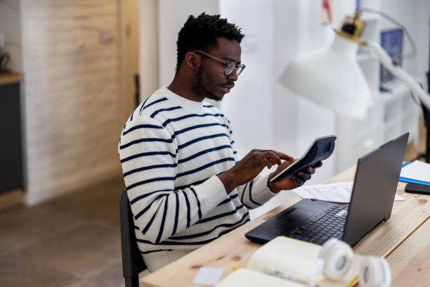 istock A young African man is working at home analyzing results with a calculator. 1492824558