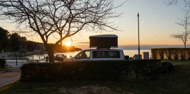 Families enjoying a warm summer's evening at a Croatian campsite on the Adriatic coast. Children are playing on the beach as the sun sets, casting a warm glow over the caravans and motorhomes