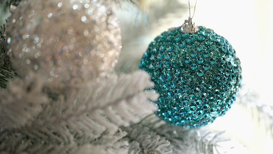 Blue and white christmas balls hanging on snow covered spruce branch closeup. Christmas tree decor concept