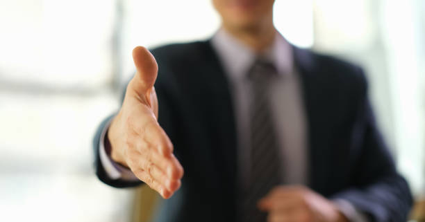 istock Businessman in suit extending his hand to partner for handshake closeup 1492827193
