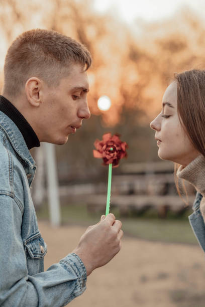 istock Young man and woman blowing on a wind toy, ecology concept 1492828408