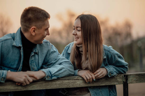 primer plano de una hermosa pareja joven sonriente en el banco del parque - human face heterosexual couple women men fotografías e imágenes de stock