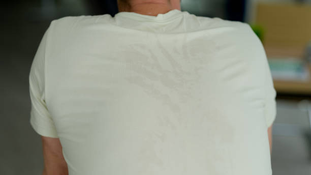 istock Back of man with light colored tshirt wet with sweat closeup 1492830332