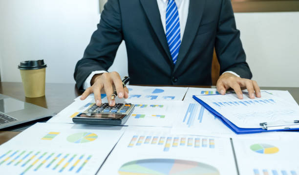 Businessman hand holding pen use a calculator, and analysis the graph with laptop at the home office for setting challenging business goals And planning to achieve the new target. el hombre de negocios que sostiene la pluma de la mano use una calculadora y analice el gráfico con la computadora portátil en la oficina en casa para establecer objetivos comerciales desafiantes y planificar para lograr el nuevo objetivo