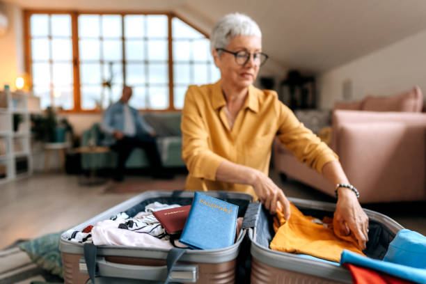 Senior woman packing suitcase for vacation