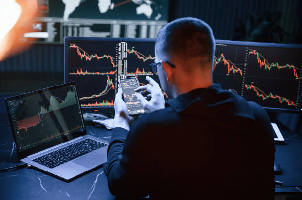 istock With smartphone in hands. Male professional hacker is sitting by computer, conception of virus 1492839197