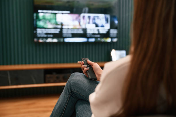 istock Woman is sitting at home watching TV, holding remote controller 1492839341