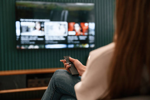 istock Woman is sitting at home watching TV, holding remote controller 1492839346