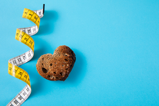 Tape measure with heart shaped bread on blue