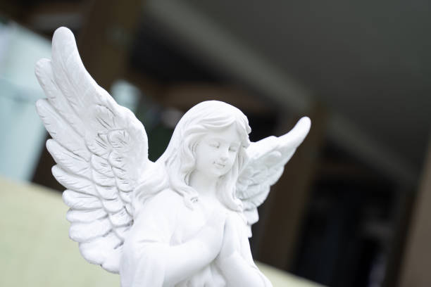 istock Cupid stucco doll, white girl, clasped hands, blurred light background 1492846385