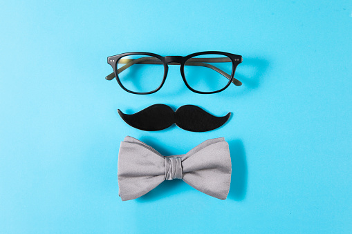 Happy Father's Day concept with eye glasses, bow tie and mustache paper  on blue background