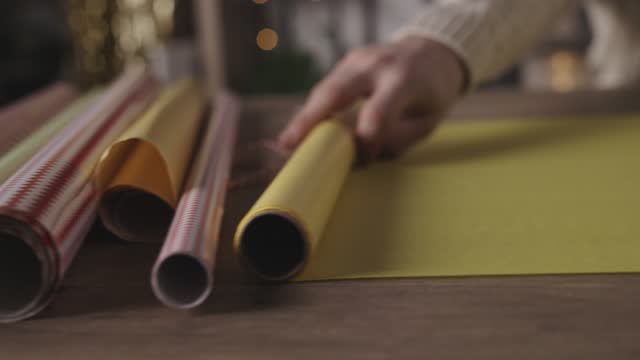 Close up shot of young man smoothly unrolling a yellow wrapping paper