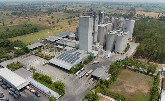 Aerial view of animal feed factory. Agricultural silos, grain storage silos, and solar panel on roofs of industrial plants. Industrial landscape. Agriculture industry. Factory with sustainable energy.