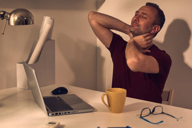 istock Man with head and neck pain while working on a laptop at home. 1492856749