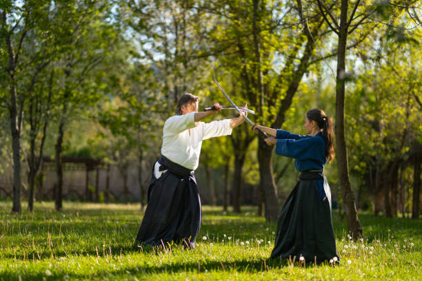 istock Male and female aikido sensei in Hakama practicing with samurai sword outdoors in the park 1492856812