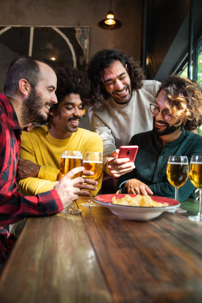 istock Multiracial male friends watching online videos with mobile phone while having drinks in a bar. 1492858064