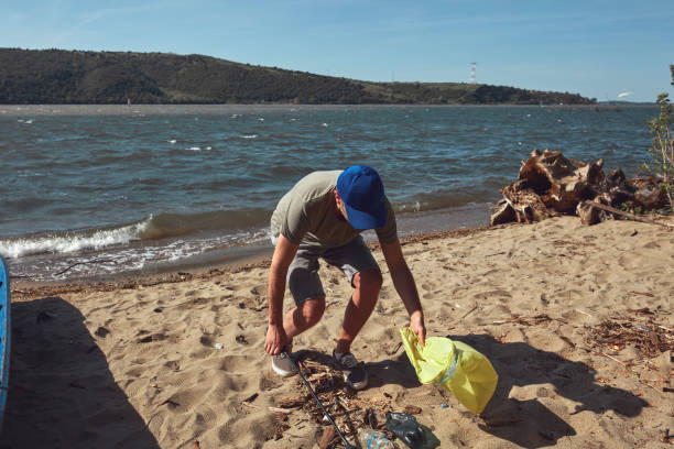 istock Volunteer and environmental activist cleaning dirty river shore filled with trash. 1492858074