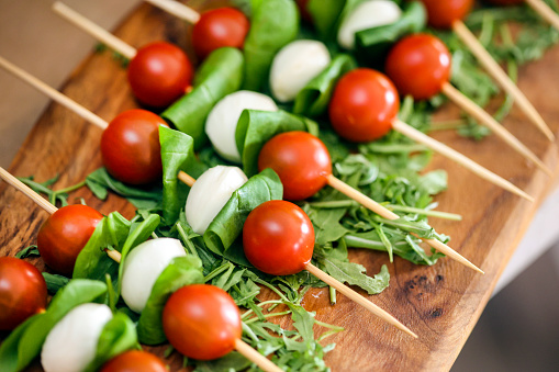 Cherry tomato and mozzarella on skewers on a buffet table.