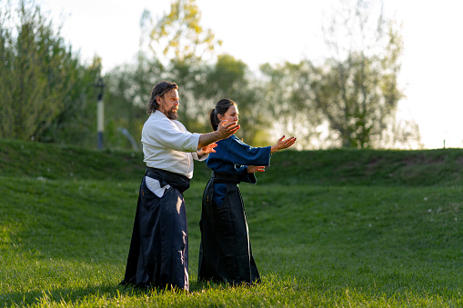 Male and female aikido sensei in Hakama practicing hand technique outdoors in the park