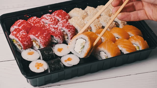 Sticks Take Sushi From the Plastic Sushi Box, Close-Up
