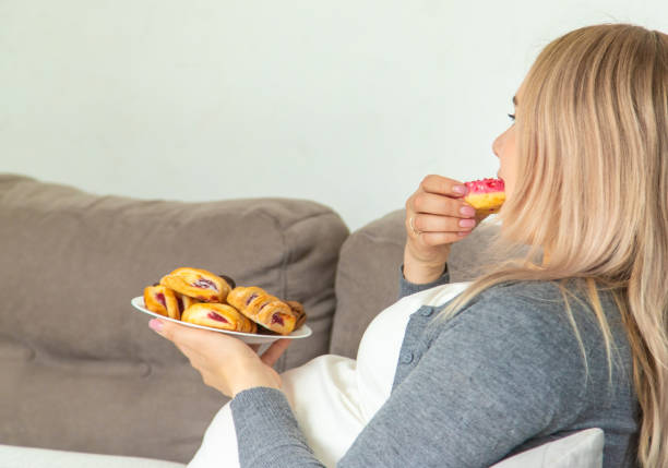 istock A pregnant woman eats a sweet donut. Selective focus. 1492867061