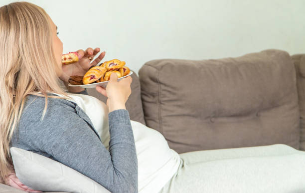 istock A pregnant woman eats a sweet donut. Selective focus. 1492867065