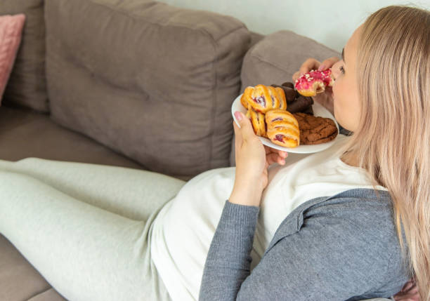 istock A pregnant woman eats a sweet donut. Selective focus. 1492867072