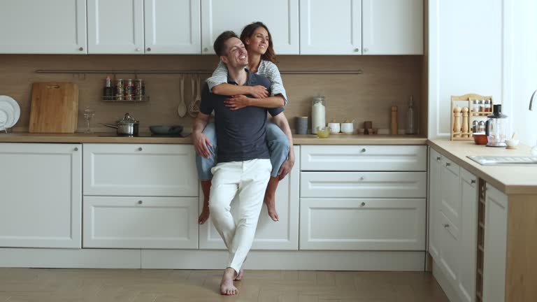 Happy Hispanic couple hugging, spend time in modern kitchen