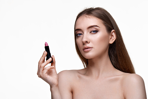 beautiful young smiling woman holding pink lipstick isolated on white background