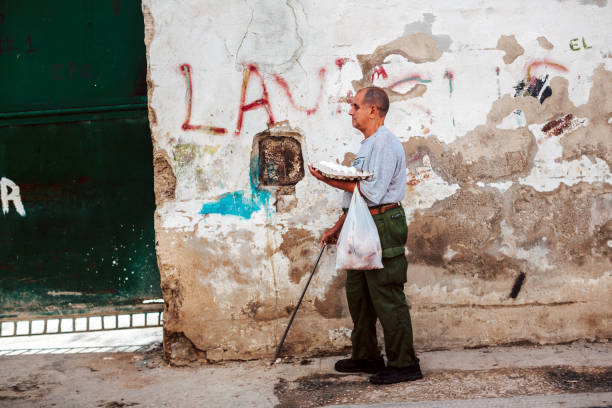 Blind cuban man holding eggs and meat walking on the sidewalk in Havana, Cuba stock photo
