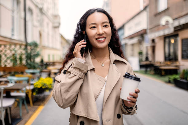 istock Smiling businesswoman walking outdoors talking on smart phone drinking coffee 1492872532