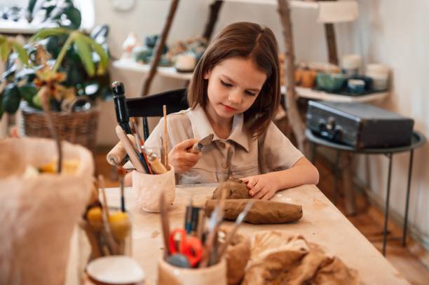 istock Working with clay. Little girl is learning how to do pottery in the workshop 1492873203