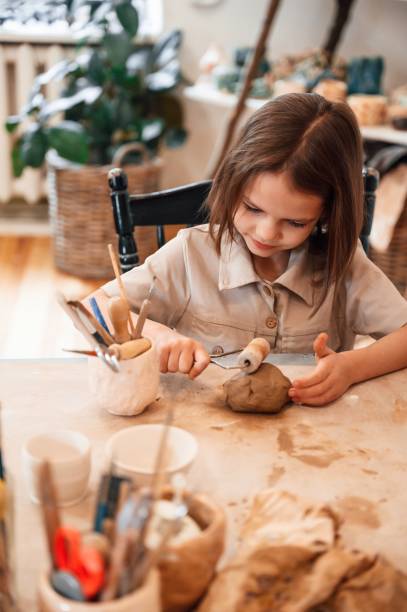 istock Working with clay. Little girl is learning how to do pottery in the workshop 1492873226